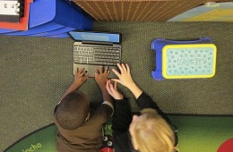 Fifth grade student teaches a younger student how to use a Chromebook